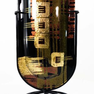 Face of this powerful, mini-vase. Made of fused glass and featuring a versatile but strong color palette and design, this piece can accommodate a variety of interiors, though more masculine, dark colors, black, and darker hardwoods are among the more natural fits for this piece.