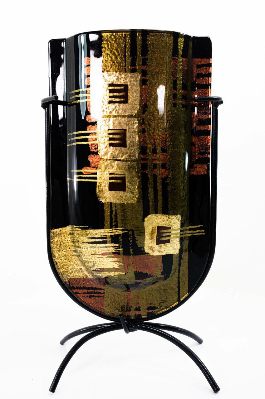 Face of this powerful, mini-vase. Made of fused glass and featuring a versatile but strong color palette and design, this piece can accommodate a variety of interiors, though more masculine, dark colors, black, and darker hardwoods are among the more natural fits for this piece.